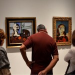 Visitantes apreciando as obras "Busto e Paleta" (1925) e madeira "Retrato de Dora Maar" (1939), todas de Pablo Ruiz Picasso.